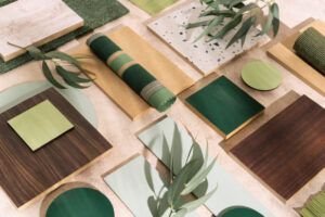 A collection of material samples in shades of green and wood, with eucalyptus leaves.