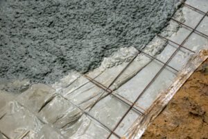 Wet concrete is poured over ground rebar, showing early concrete construction.